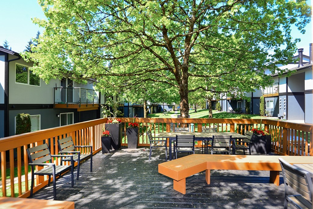 an outdoor patio with a tree and tables and chairs