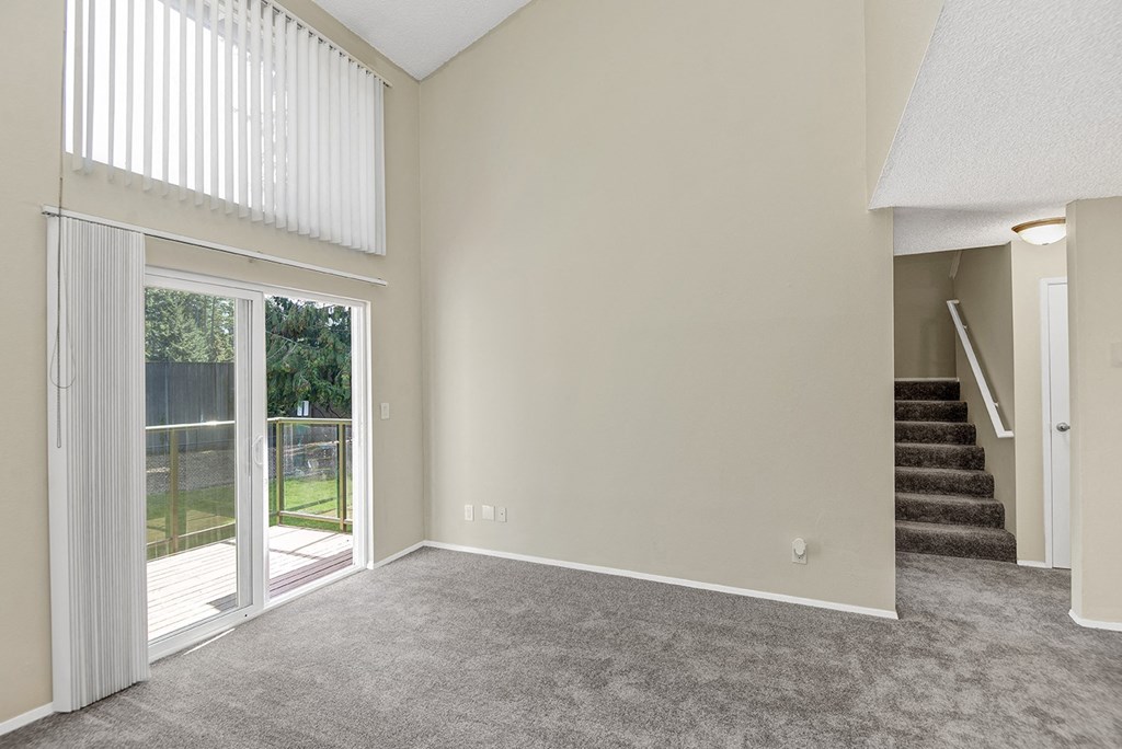 an empty living room with a sliding glass door leading to a patio