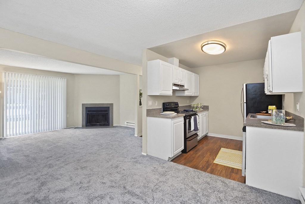 a living room with a fireplace and a kitchen