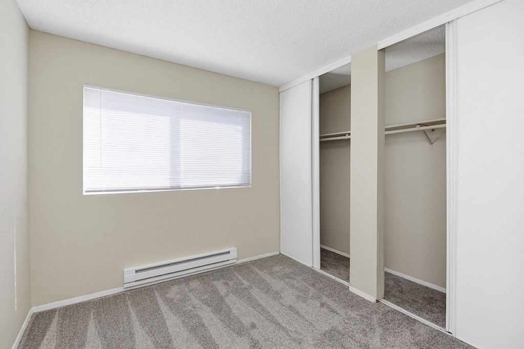 a bedroom with an empty closet and a large window