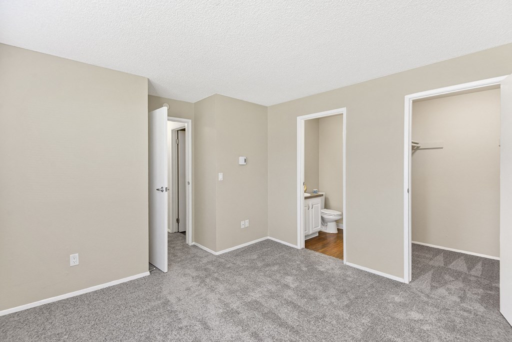 a bedroom with three doors and a bathroom in the background