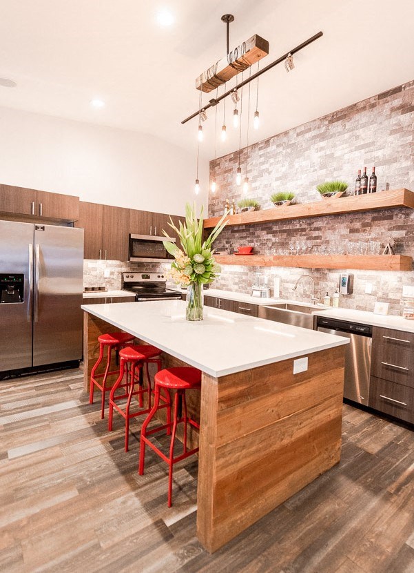 A kitchen with a white counter top and red bar stools.