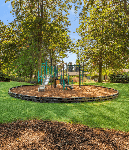 A playground with a green slide and a brown sandbox. at The Retreat, Sumner, WA
