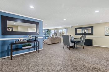 A living room with a blue accent wall and a large mirror. at The Verandas, Washington, 98466