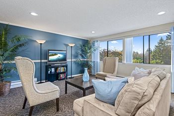 A living room with a chair, a sofa, a table, and a television. at The Verandas, Tacoma, Washington