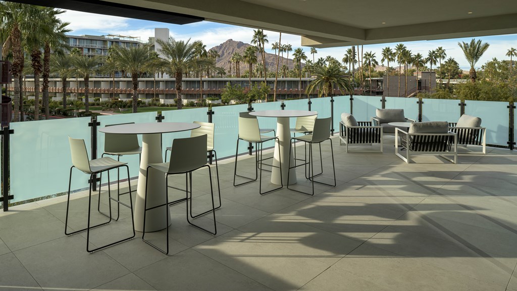 A patio with white chairs and a table with a blue wall.
