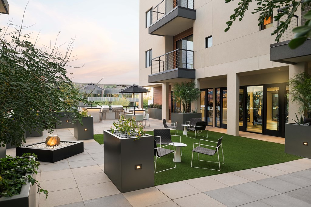 A modern patio with a fire pit and seating area.