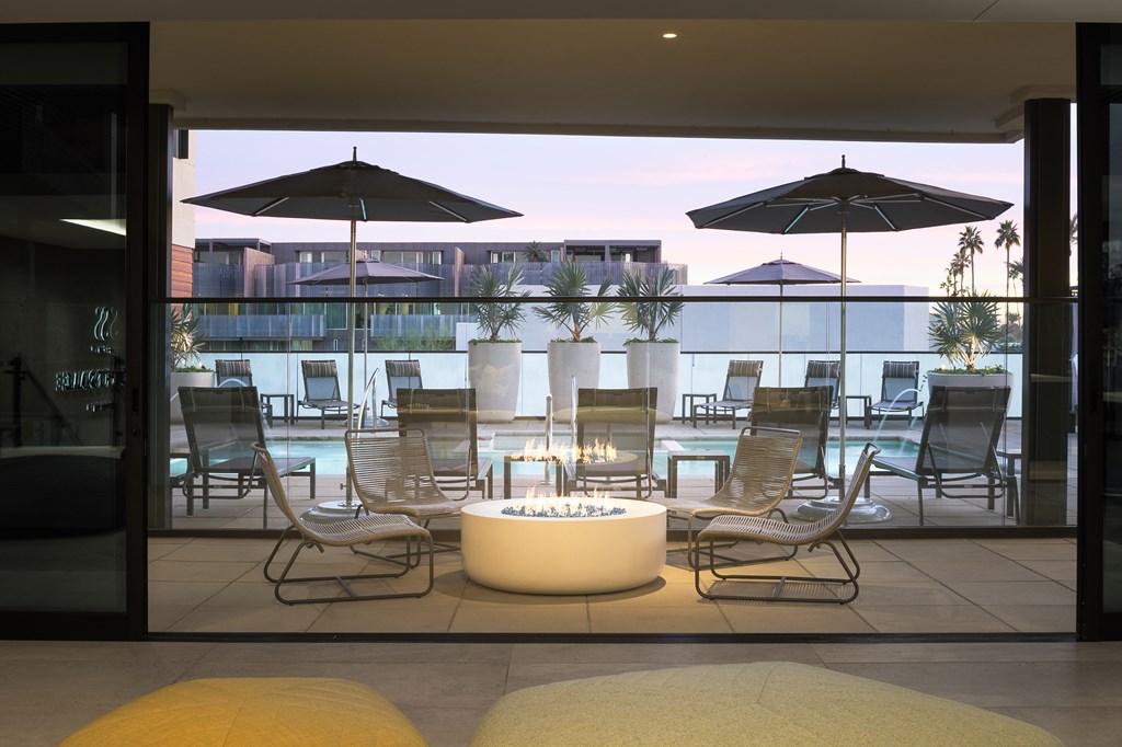 A modern outdoor seating area with a fire pit and chairs.