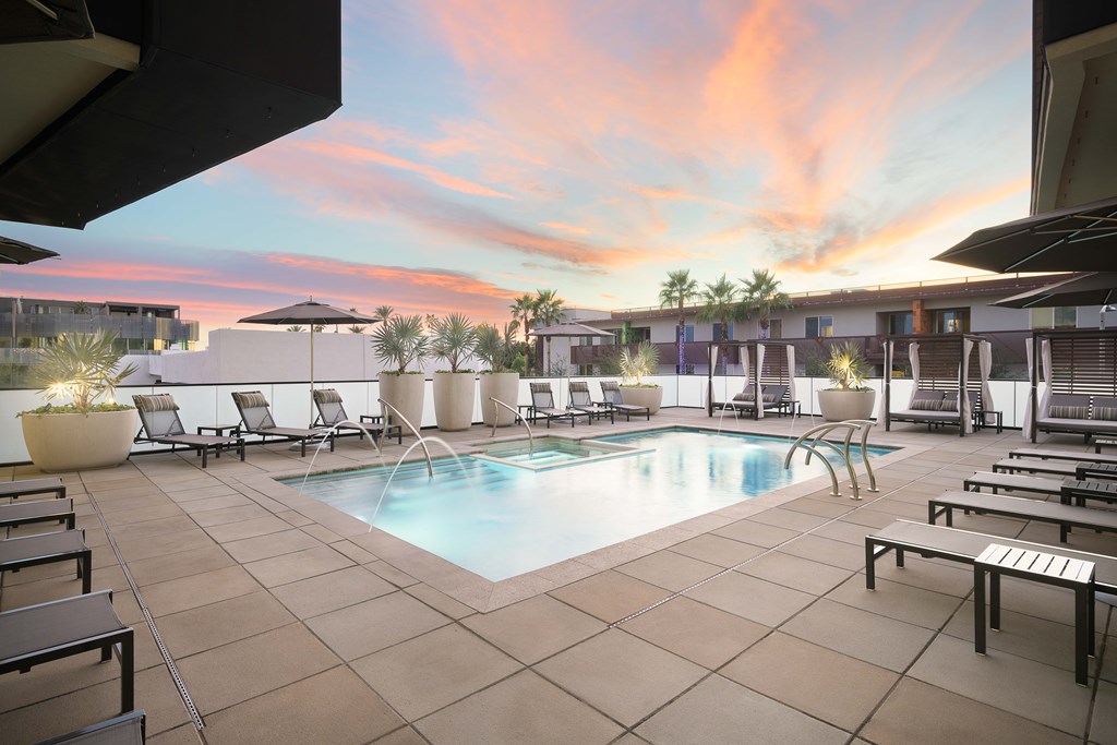 A pool surrounded by lounge chairs and umbrellas.