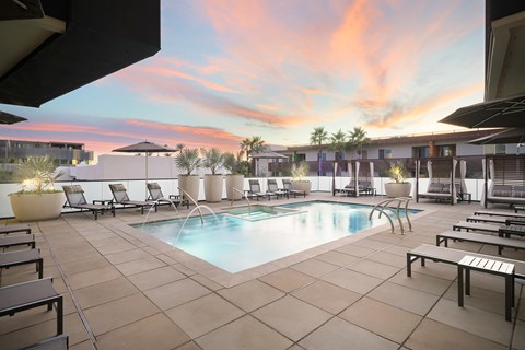 A pool surrounded by lounge chairs and umbrellas.