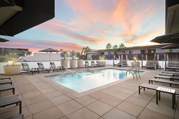 A pool surrounded by lounge chairs and umbrellas.