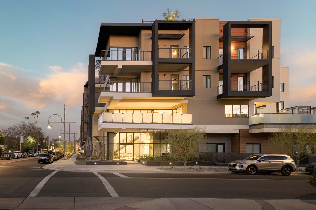 A modern apartment building with cars parked in front.