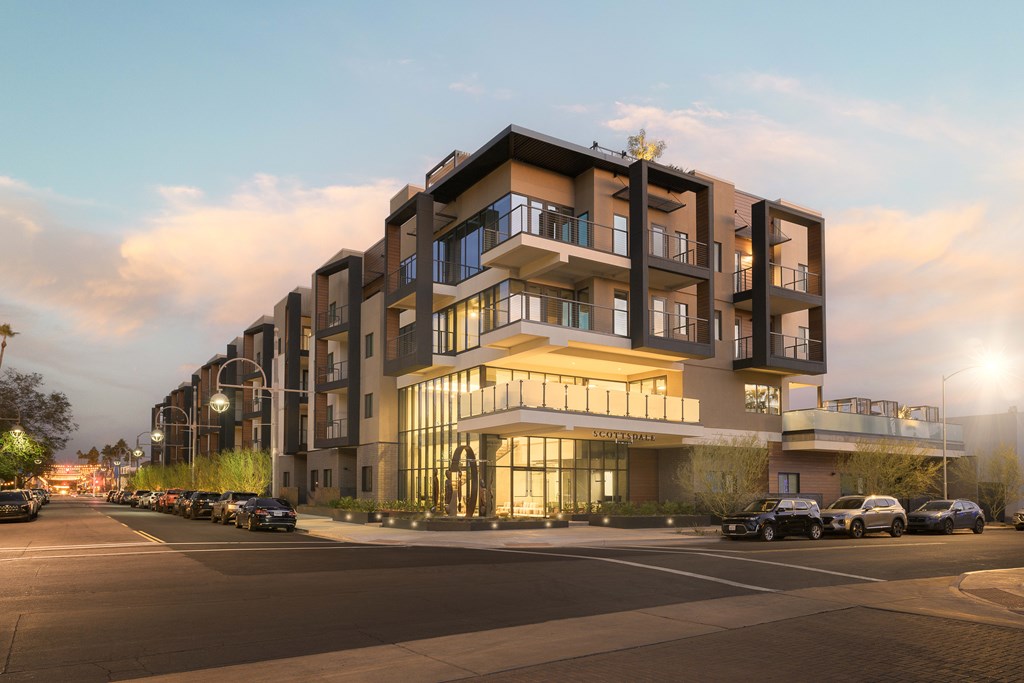 A modern apartment building with cars parked in front.