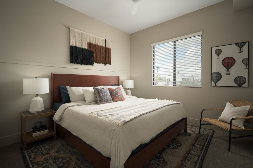 A bedroom with a bed, a chair, and a window.