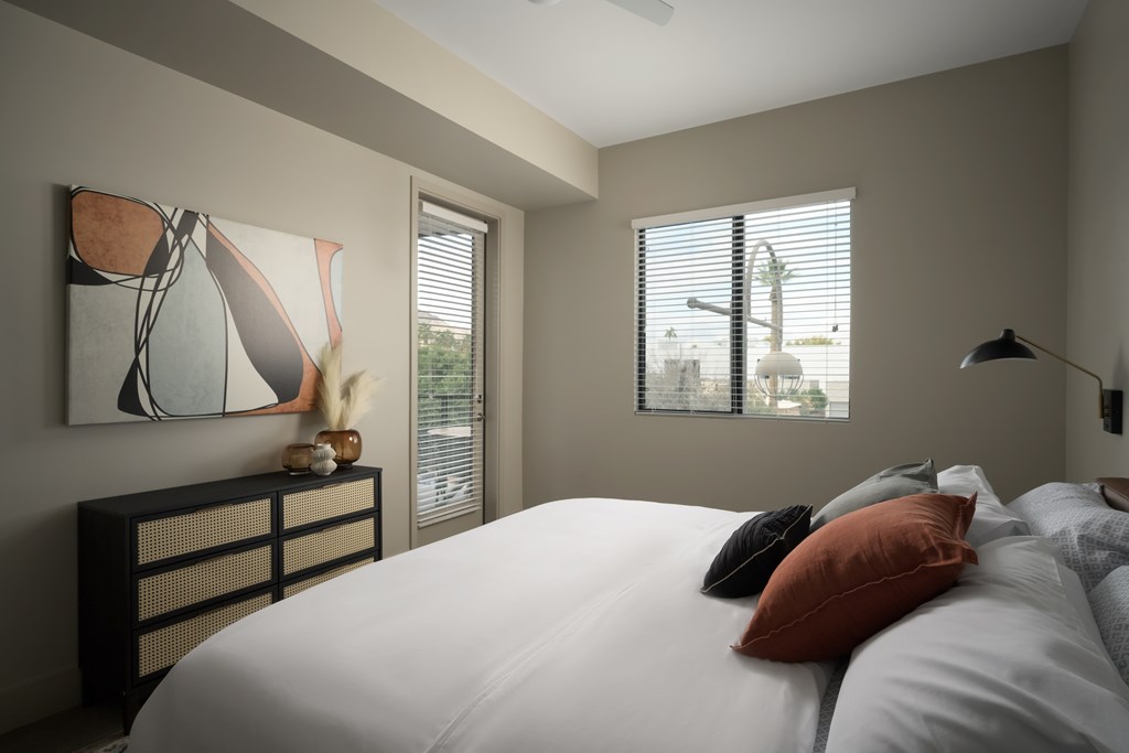 A bedroom with a large bed and a painting on the wall.