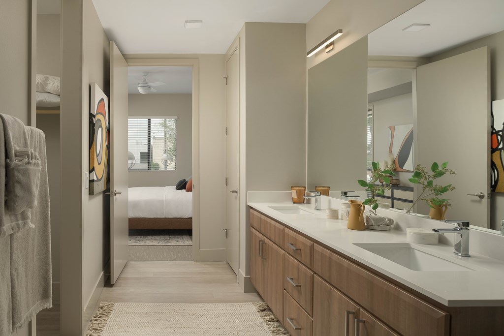 A bathroom with a white counter top and a mirror above it.