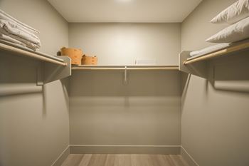 A small, empty closet with a wooden floor and white walls.