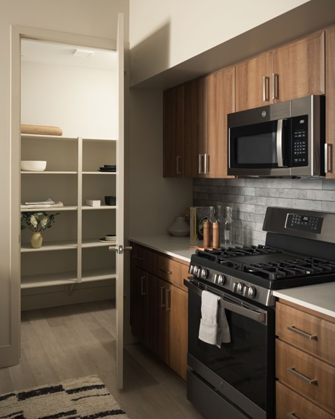 A modern kitchen with a black stove and wooden cabinets.