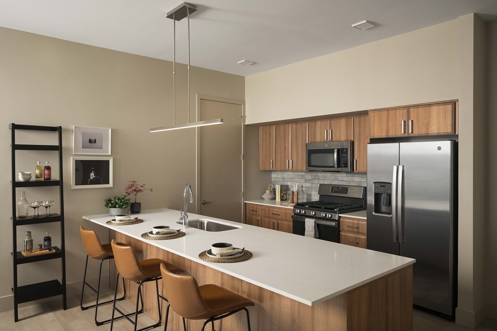A modern kitchen with a white countertop and stainless steel appliances.