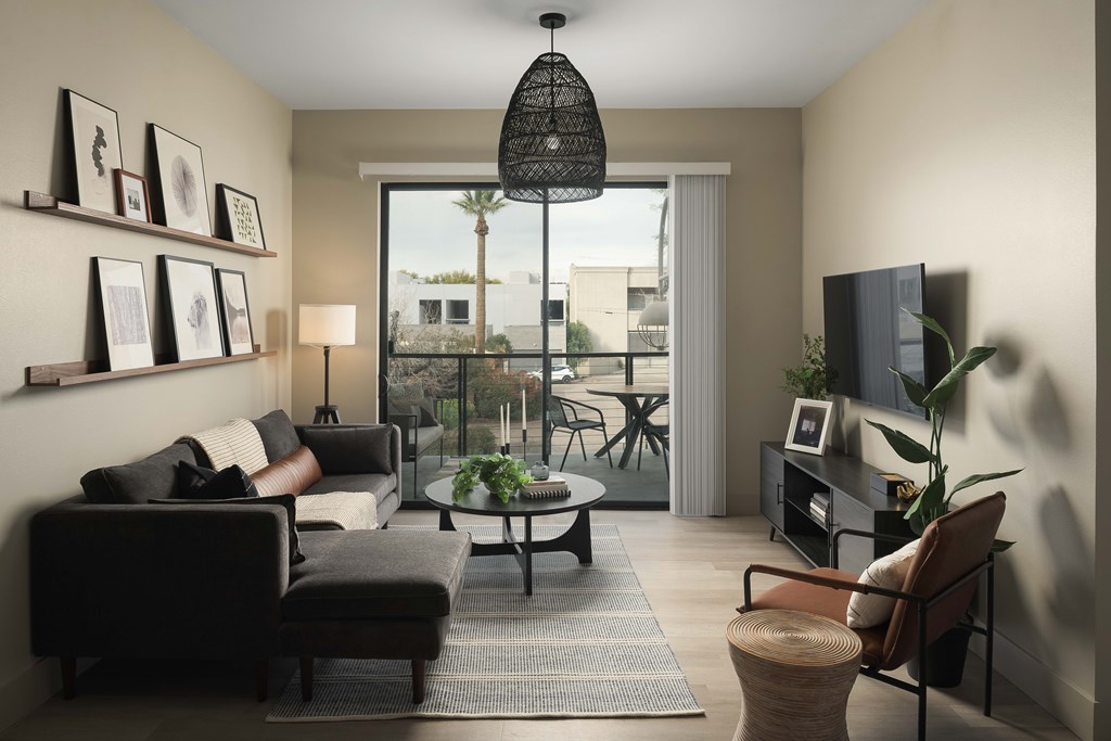 A living room with a black couch, a coffee table, and a flat screen TV.