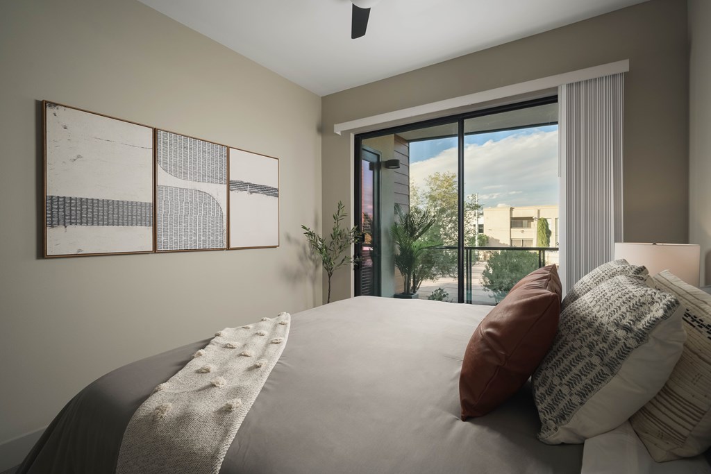 A bedroom with a large bed and a view of the city through the window.