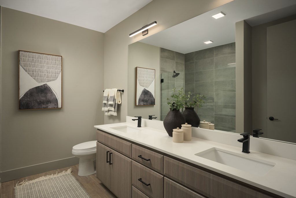 A bathroom with a toilet, sink, and mirror.