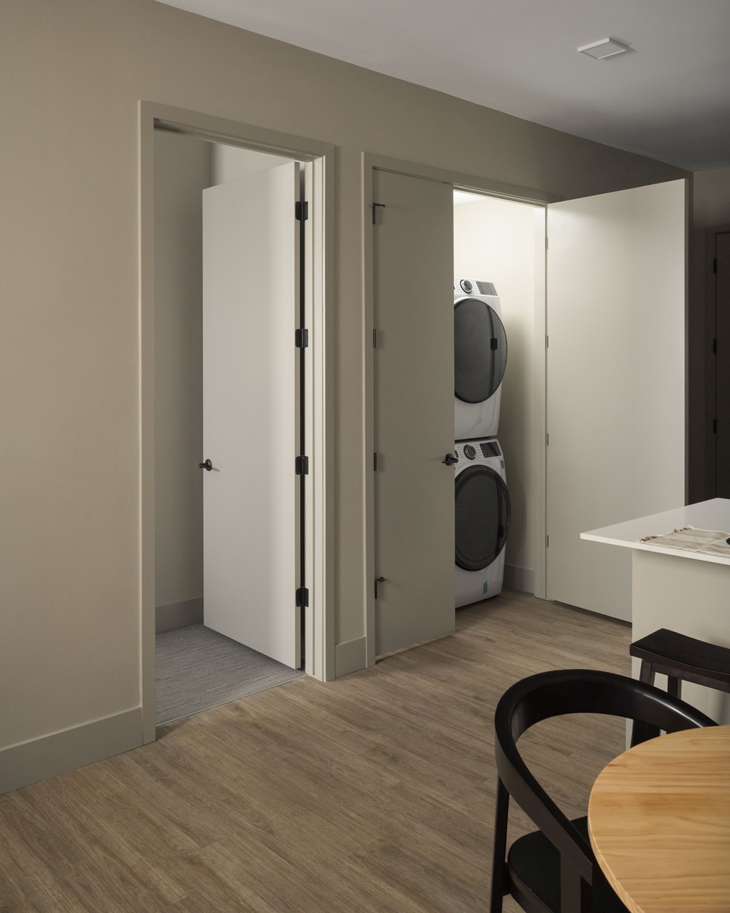 A modern kitchen with a table and chairs and a washing machine in the background.