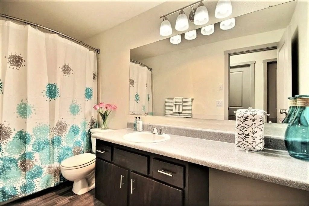 A bathroom with a floral shower curtain and a white sink. at The Retreat, Sumner, Washington