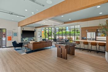 a communal area with a kitchen and a living room with a bar and a table