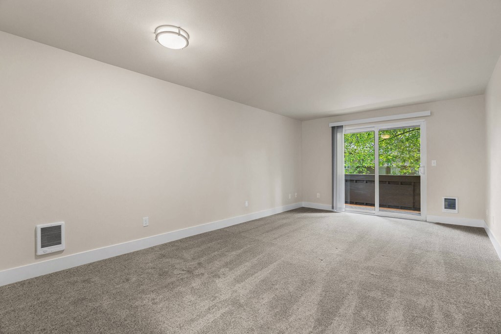 an empty living room with a large window and carpeting at Bellamy Park Apartments , Washington