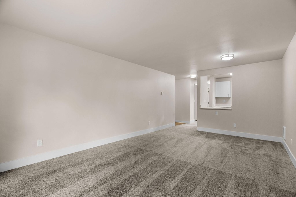 an empty living room with carpet and white walls at Bellamy Park Apartments , Lakewood