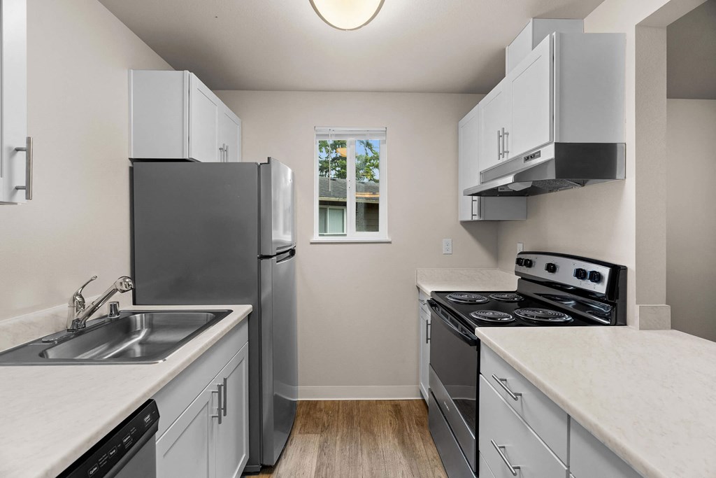 an empty kitchen with white cabinets and stainless steel appliances at Bellamy Park Apartments , Lakewood, CA