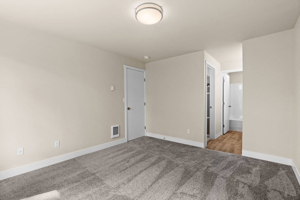 an empty living room with carpet and white walls at Bellamy Park Apartments , Lakewood
