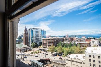 A cityscape with a clock tower is visible through a window at Addison on Fourth Apartments, Seattle, WA, 98104
