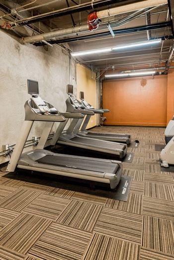 A gym with treadmills and a wall-mounted monitor at Addison on Fourth Apartments, Washington, 98104