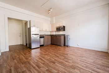 A kitchen with wooden floors and white walls at Addison on Fourth Apartments, Seattle