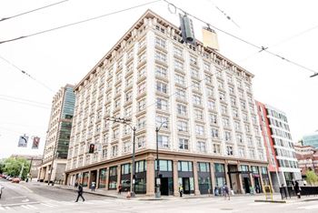 A large, old building with many windows is in the middle of a city street at Addison on Fourth Apartments, Washington