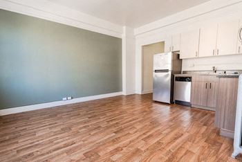 A kitchen with a refrigerator, oven, and cabinets at Addison on Fourth Apartments, Seattle, Washington