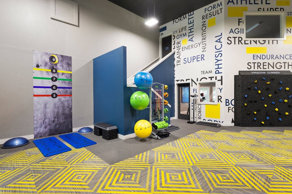 A gym with a blue and yellow floor and a variety of equipment.