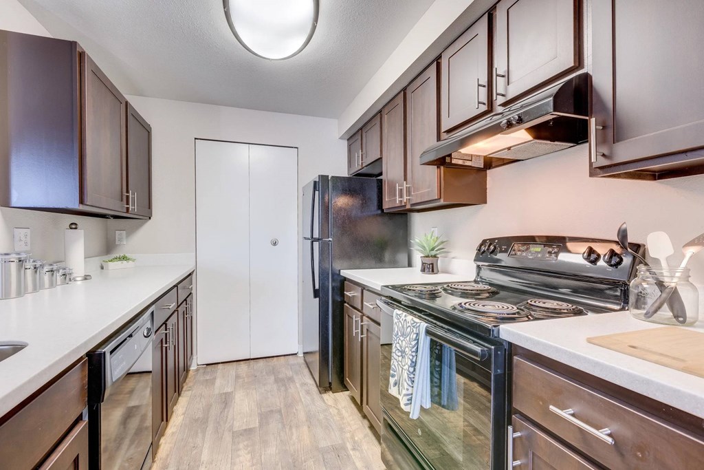 A kitchen with dark brown cabinets and a black refrigerator.