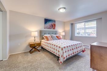 A bedroom with a bed, nightstand, and lamp.