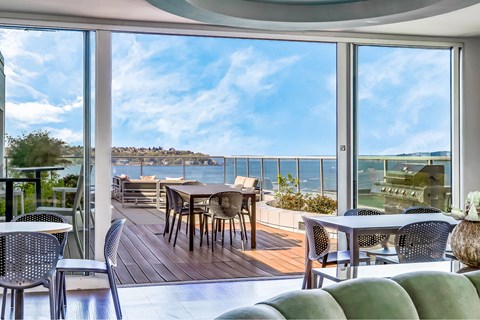 A patio with a table and chairs overlooking a body of water.
