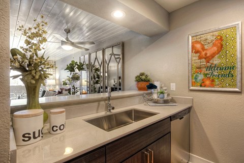 A kitchen with a white counter top and a painting on the wall.