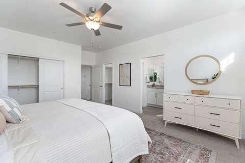 A bedroom with a large bed, a dresser, and a mirror.