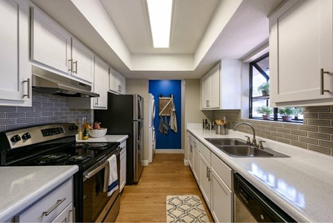 A kitchen with white cabinets and a black refrigerator.