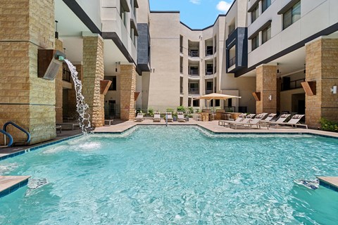 A large swimming pool with a waterfall feature in the middle.
