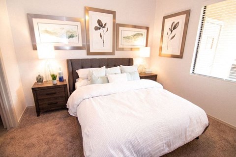 A bedroom with a large bed and three framed pictures on the wall.