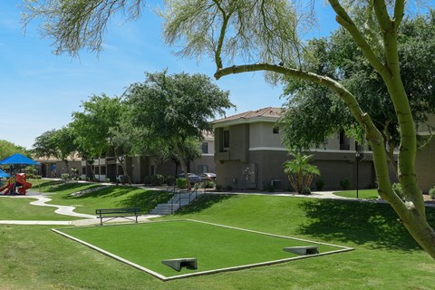 A park with a playground and a building in the background.