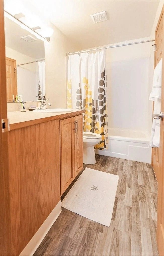 A bathroom with wooden cabinets and a white shower curtain. at The Retreat, Sumner, 98390