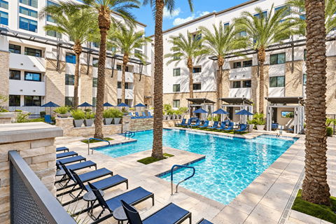 A pool surrounded by palm trees and lounge chairs.